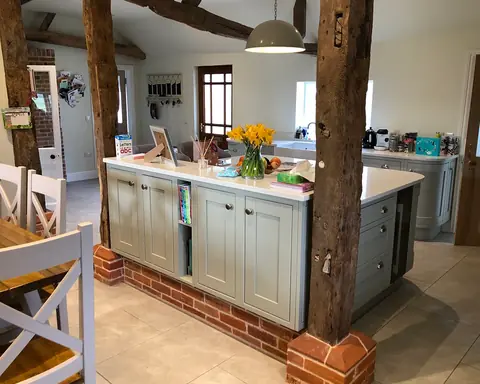 Painted island kitchen between oak beams