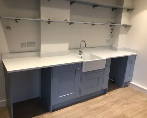 Navy shaker base units with a white worktop and Belfast sink