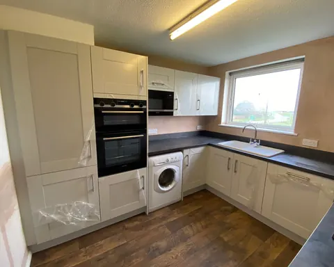 Cream shaker kitchen with a built-in oven and dark worktops